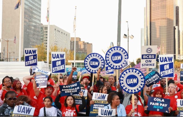 I lavoratori dell'United Auto Workers protestano in strada con striscioni "UAW on strike".