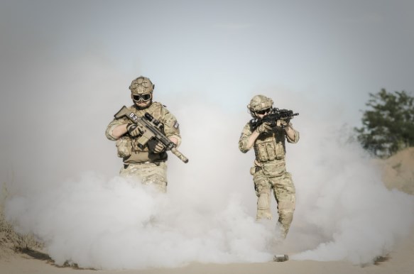 Soldati che puntano le armi all'interno di una nuvola di fumo.