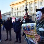 Un uomo con una maschera da clown tiene uno striscione "sciopero generale".